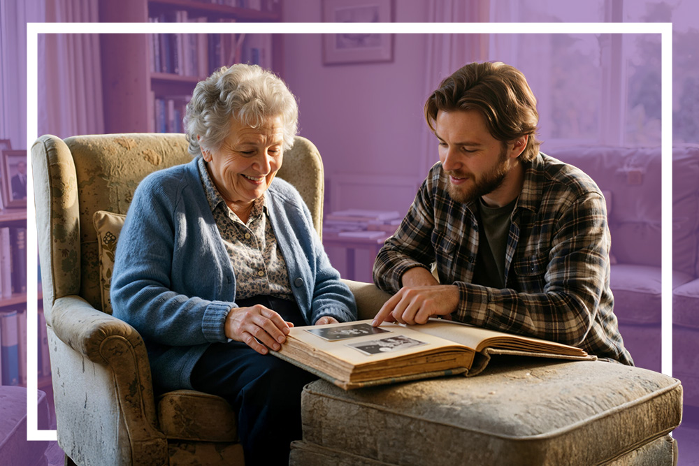 Senior woman and younger man look through an old photo album in a comfortable living room.